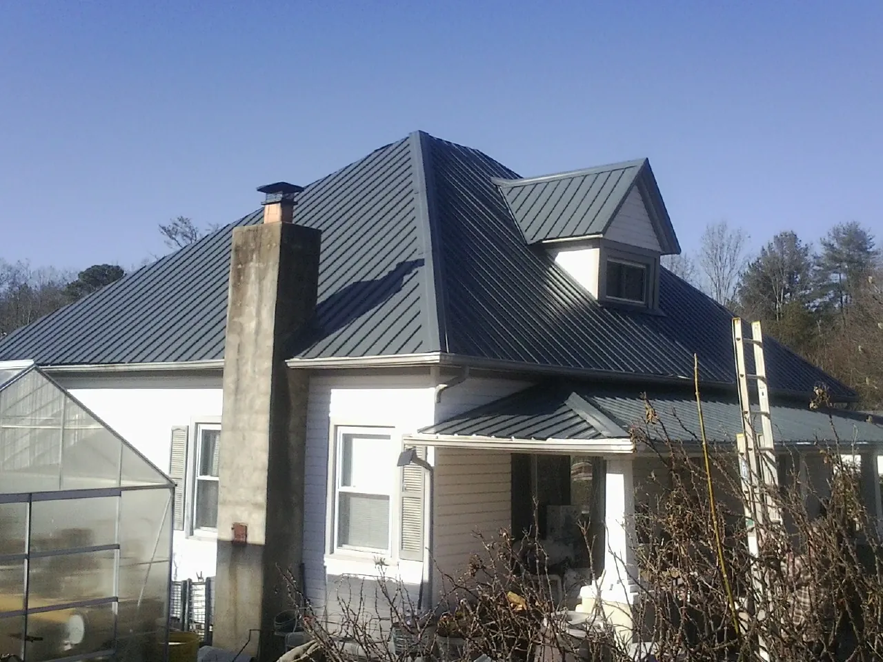 Dark blue standing seam metal roof on a white farmhouse with dormer — Slate & Tile Roof Repair by Roofing Brothers in Coulee City