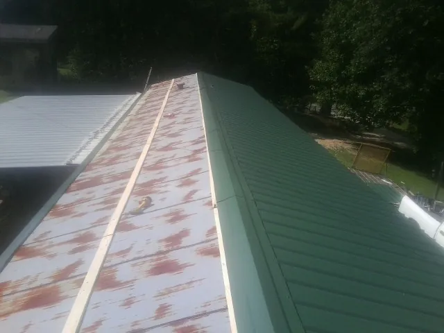 Old rusted panels beside newly installed green metal roofing — Wind Damage Roof Repair by Roofing Brothers in Coulee City