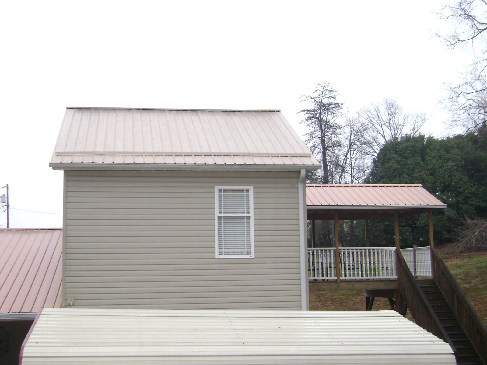 Tan metal roofs on a two story addition and attached porch, from a Roof Replacement job in Coulee City